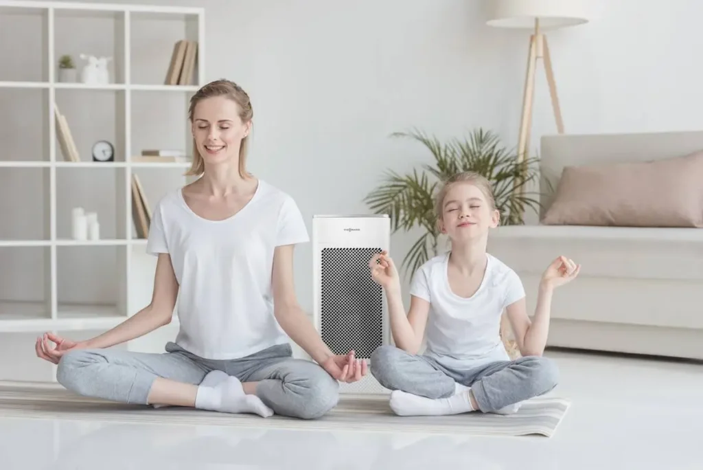 Matka z córką medytujące w salonie. W tle oczyszczacz powietrza Viessmann V-Air 100. Materiały producenta Viessmann